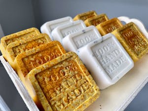 Handmade artisan soaps with '100% Hand Made' text, showcasing organic ingredients and craftsmanship.